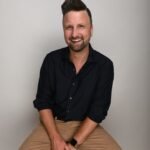 a man sitting on a stool with his legs crossed